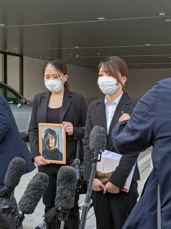 刑事裁判のあと、亡き父の遺影を手に各メディアの質問に答える長女の杏梨さん（左）と次女（筆者撮影）