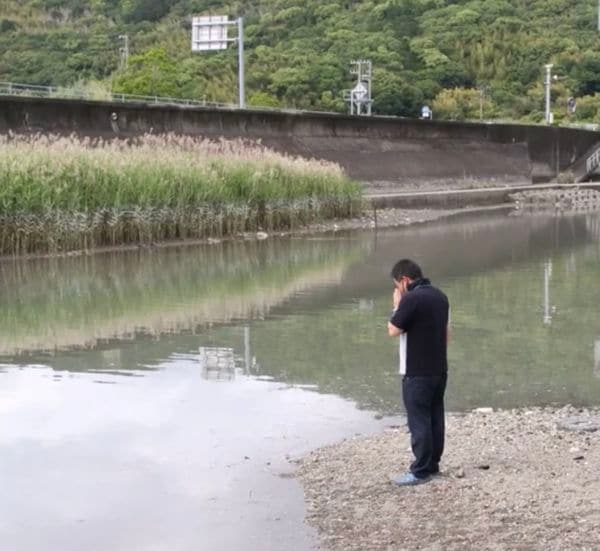 優空君が亡くなった下田川の現場で手を合わせる岡林さん（遺族提供）