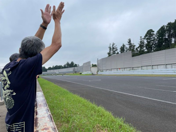 午前中、念願のバイクでサーキット走行を行う古谷さんに大きな拍手を送る丸野さん（筆者撮影）