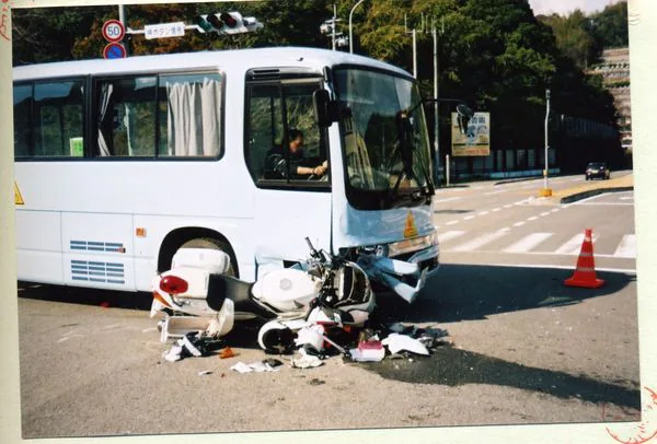 事故直後の様子。スクールバスの右前方に衝突した白バイが大破している（片岡さん提供）
