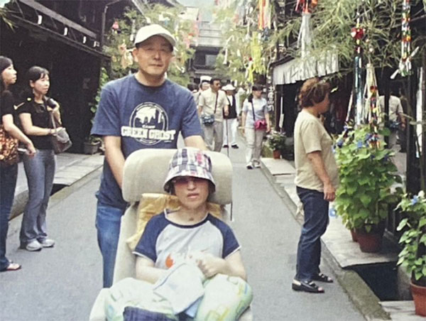 シートが車椅子になる福祉改造車、新幹線、飛行機などを使って、家族旅行にもよく出かけた。オーストラリア・ケアンズへの海外旅行に挑戦したことも。写真は飛騨高山で忠一さんと（奥村さん提供）