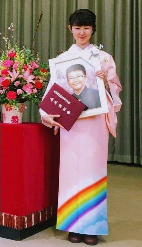 小4のとき交通事故で亡くなった息子の遺影を抱き、卒業式に虹模様の着物で出席した母親の理絵さん（理絵さん提供）
