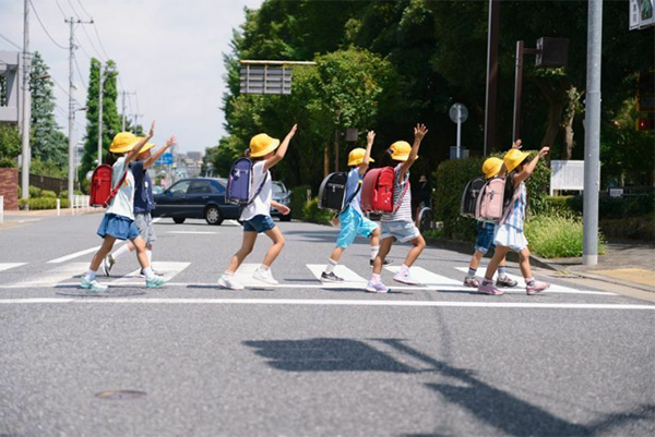 手を上げて横断歩道を渡る小学生たち（写真:アフロ）