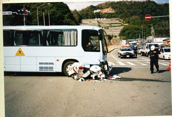 事故直後の様子。スクールバスの右前方に衝突した白バイが大破している（バス運転手の男性提供）