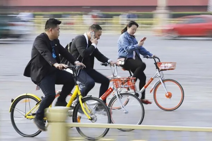スマートフォンを使いながら自転車に乗る人たち＝中国・北京。2017年4月（写真：共同通信社）